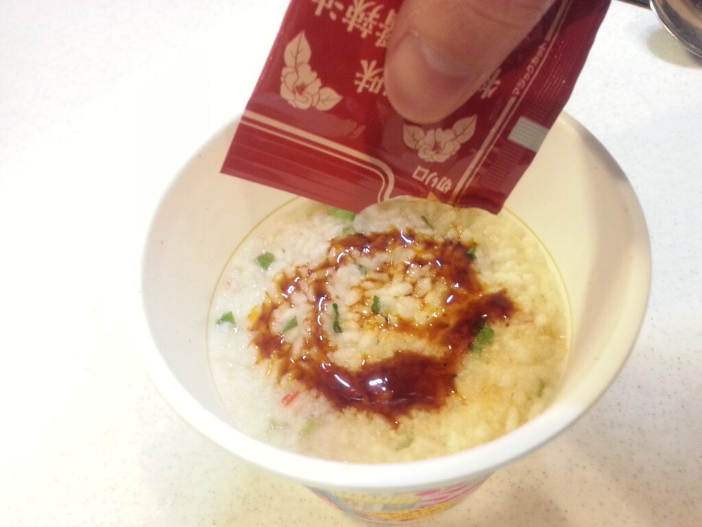 日清食品「台湾メシ・鹹豆漿粥」ラー油を加える様子
